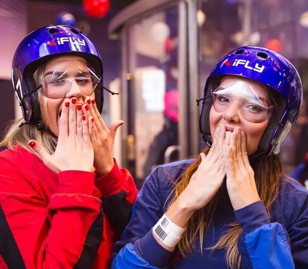 Two flyers in helmets and goggles laughing together after a flight