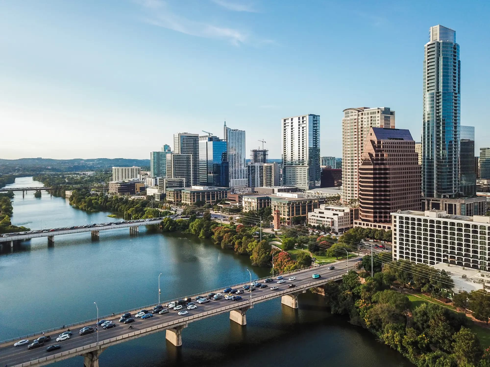 Aerial view of downtown Austin at golden hour, with traffic crossing the Congress Avenue Bridge over Lady Bird Lake