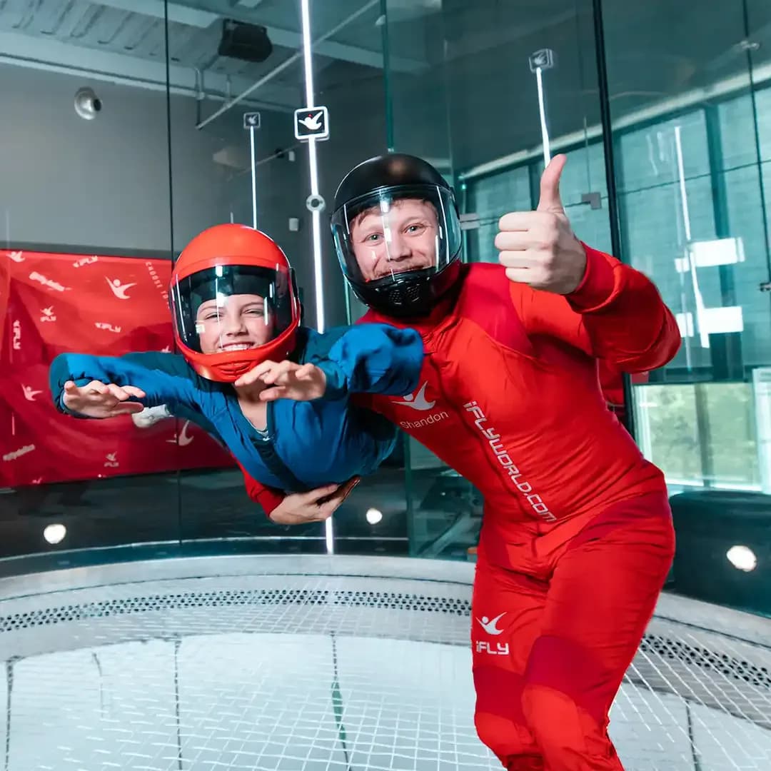 A young flyer confidently flies while their instructor gives a thumbs up