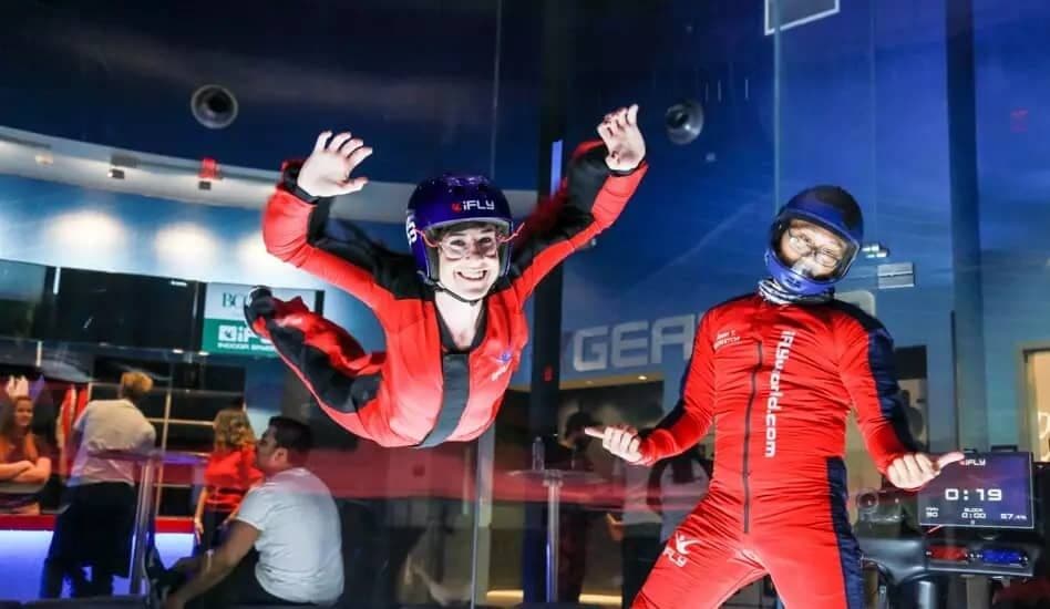 Customer flying in tunnel while instructor gives thumbs up