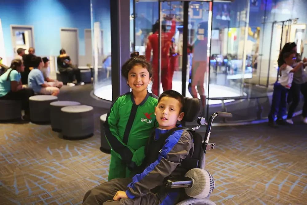 Two students in flight gear smiling in front of the tunnel