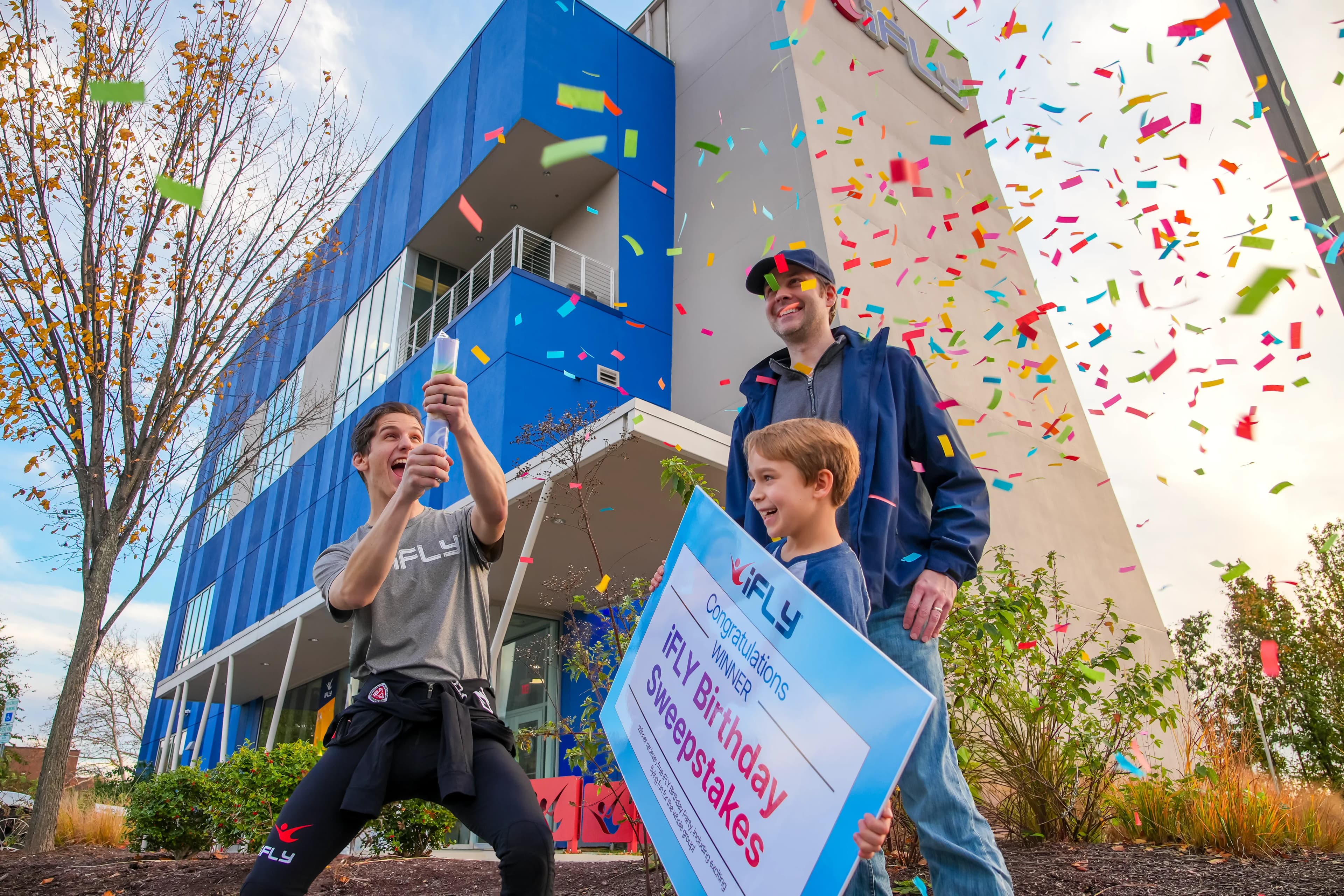 A father celebrates winning the birthday sweepstakes with his two sons shooting confetti