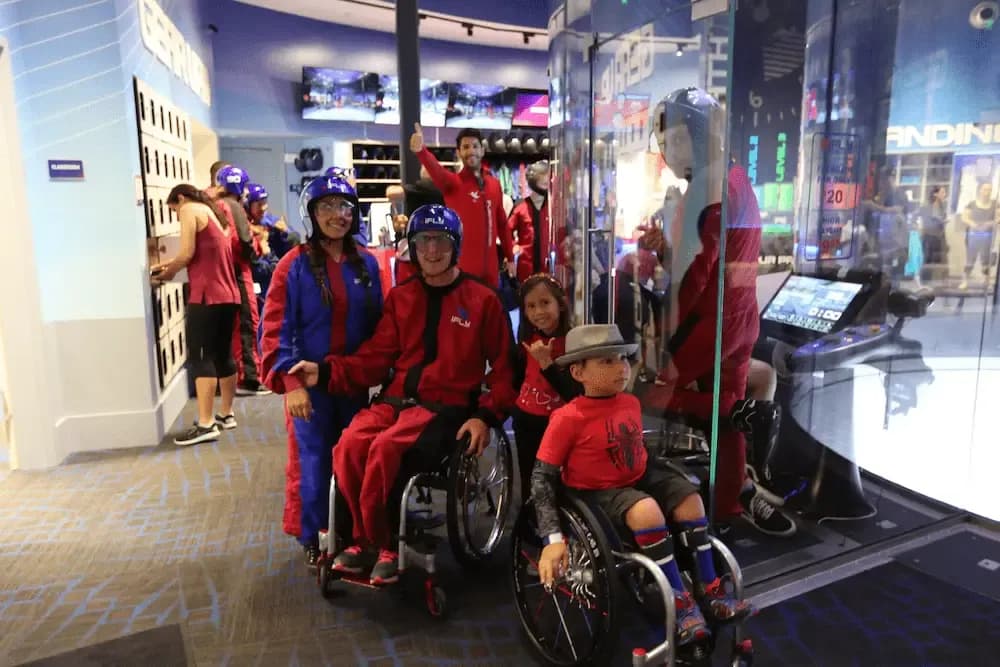 A group of people in red and blue jumpsuits, some in wheelchairs, smiling indoors.