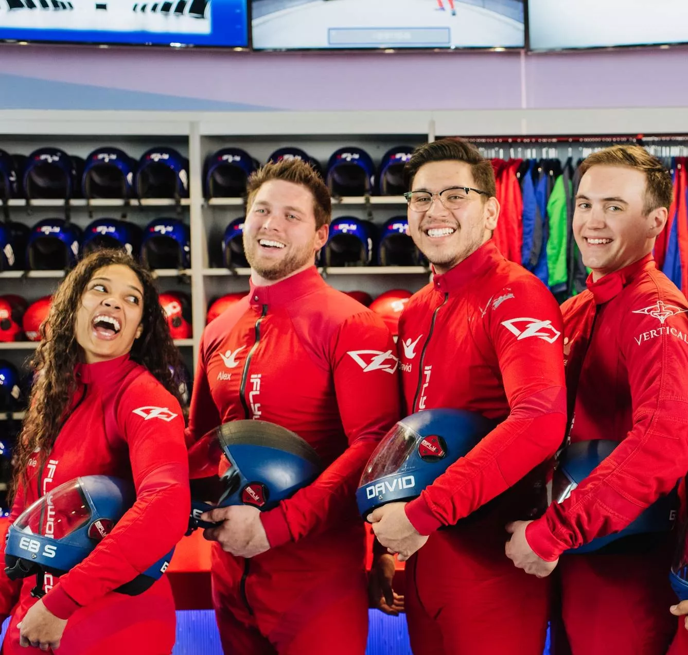 Four smiling young adults posing with iFLY skydiving gear