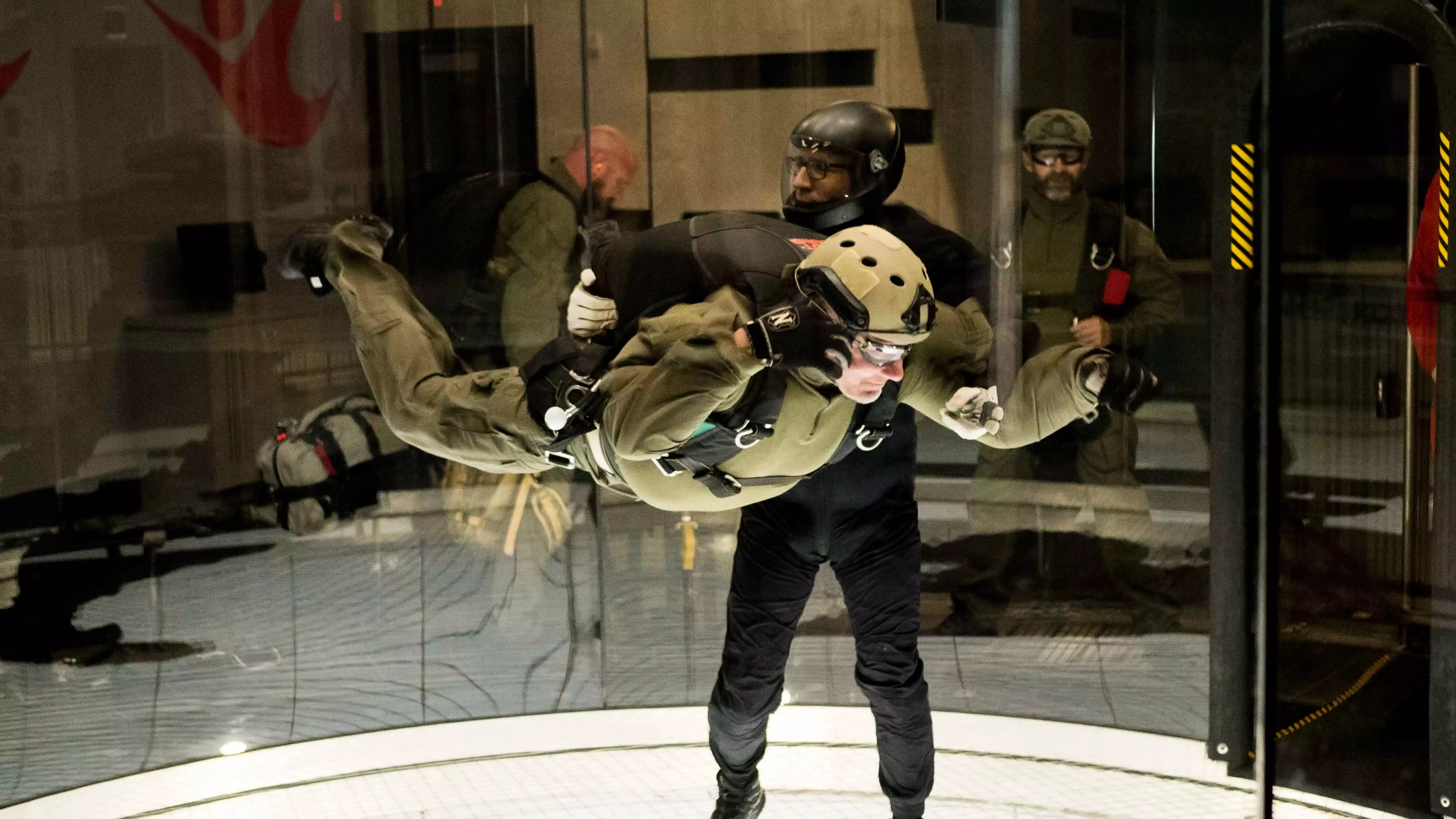 Military man flying in iFLY tunnel with an instructor by his side.