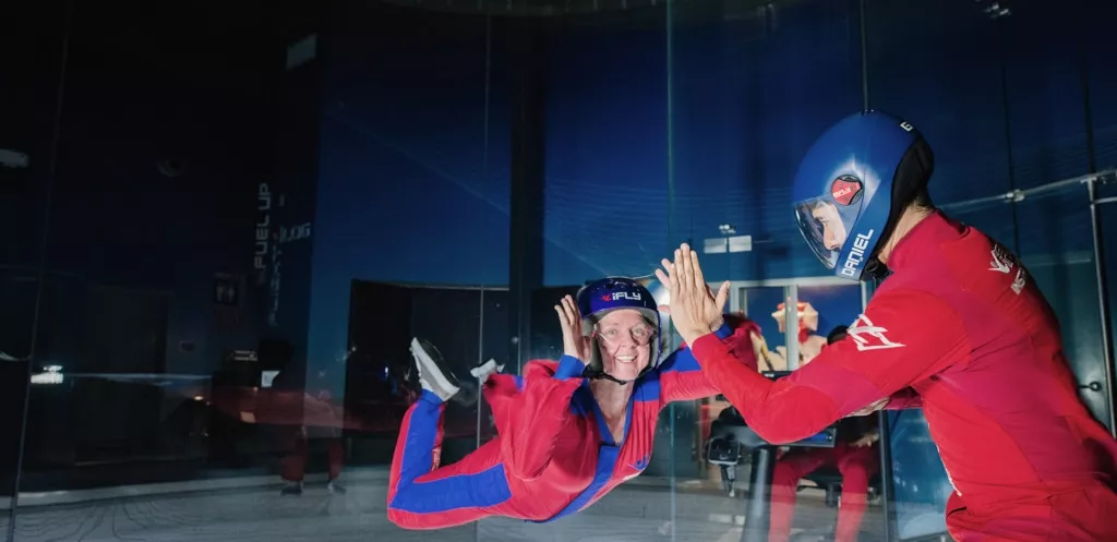 iFLY instructor giving a high five to a smiling female flyer